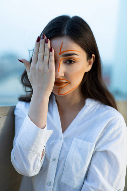 Portrait of young woman with painted face covering eye with hand . High quality photo - Photo, Image