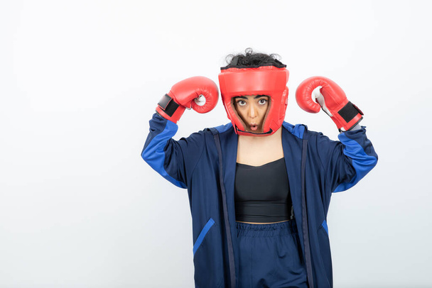 Photo of fit female boxer in red gloves and helmet training. High quality photo - Фото, изображение