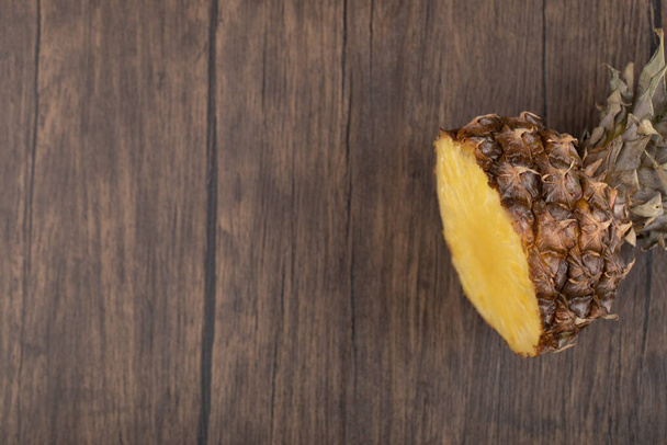 Ananas affettato con la sua corona di foglie tagliate in un unico pezzo su fondo di legno. Foto di alta qualità - Foto, immagini