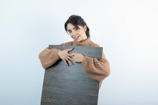 Beautiful woman in brown knitwear holding piece of wood. High quality photo - Zdjęcie, obraz