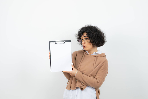 Portrait of young woman in glasses holding empty clipboard. High quality photo - Photo, Image