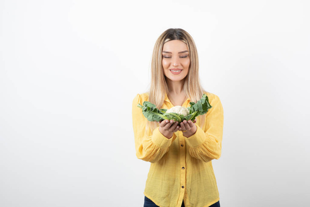 Picture of a pretty woman model standing and looking at cauliflower. High quality photo - Фото, зображення