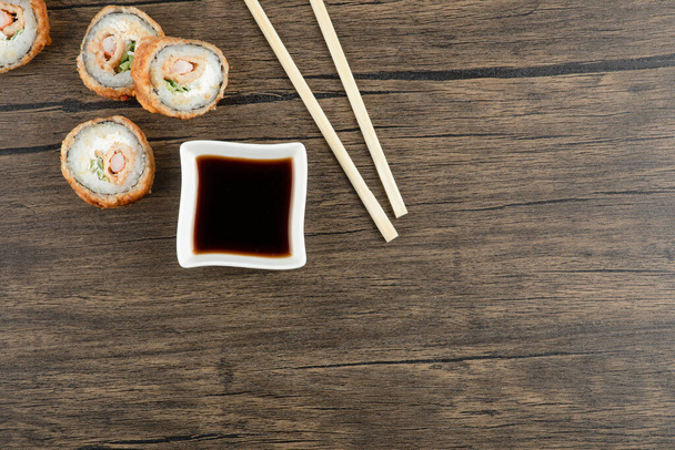 Kuuma sushi rullaa soijakastikkeella ja syömäpuikoilla puupinnalla. Laadukas kuva - Valokuva, kuva