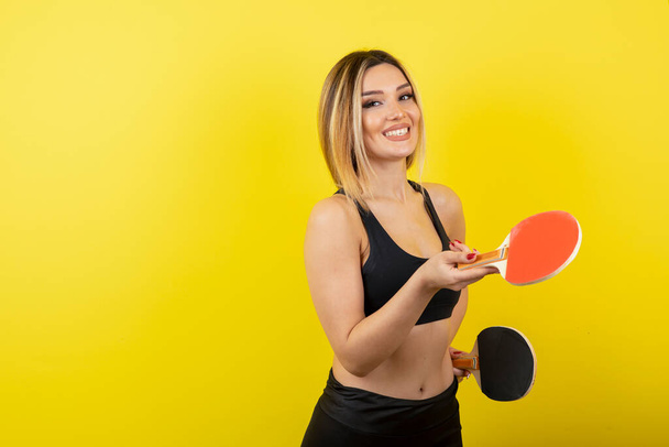 Portrait of young woman standing and holding table tennis rackets . High quality photo - Photo, Image