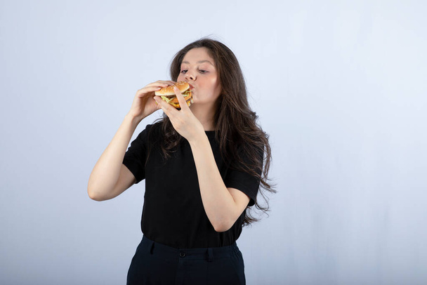 Gyönyörű fiatal nő, aki finom marhahúsos hamburgert eszik. Kiváló minőségű fénykép - Fotó, kép