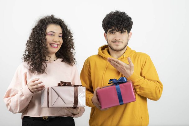 Retrato de pareja joven sosteniendo cajas de regalo sobre pared blanca. Foto de alta calidad - Foto, imagen