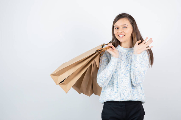 Photo d'une adolescente en pull debout et tenant des sacs en papier. Photo de haute qualité - Photo, image
