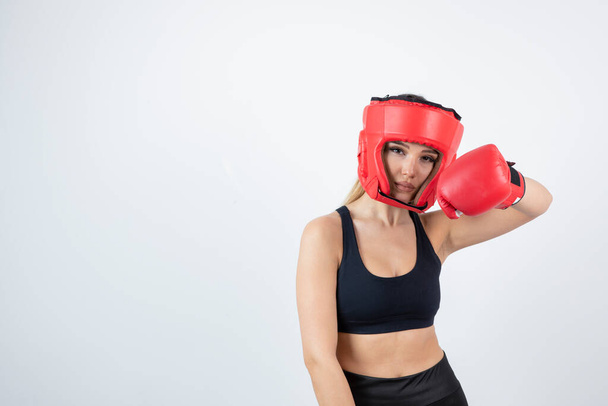 Afbeelding van jonge vrouwelijke bokser in rode handschoenen en helm gevechten. Hoge kwaliteit foto - Foto, afbeelding