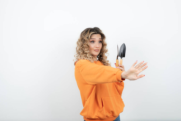 Portrait of young woman with wavy hair holding garden tools . High quality photo - Фото, зображення