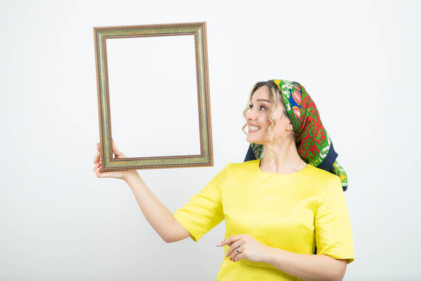 Photo of cute woman in headkerchief looking at frame . High quality photo - Photo, Image