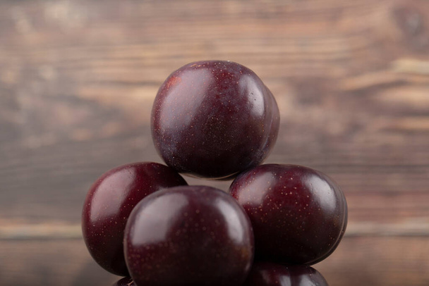 Close view of ripe juicy plums on wooden surface. High quality photo - Fotografie, Obrázek