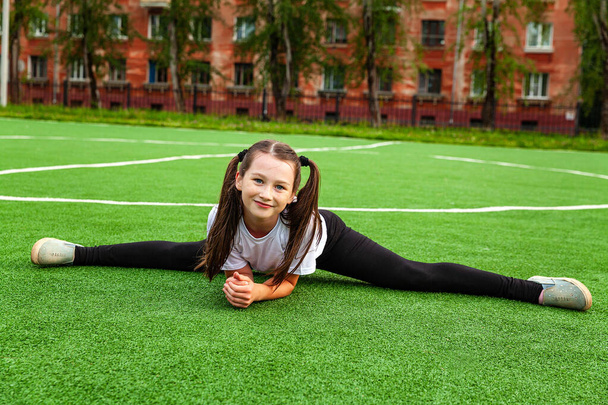 Una chica en ropa deportiva hace cordel en el estadio. Durante el día, al aire libre, gimnasia, calentamiento - Foto, Imagen