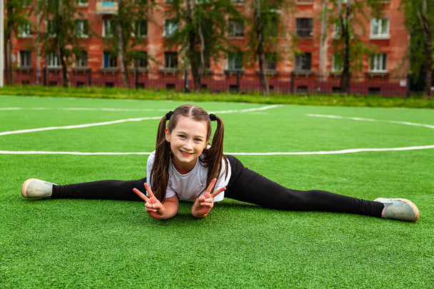 Una chica en ropa deportiva hace cordel en el estadio. Durante el día, al aire libre, gimnasia, calentamiento - Foto, Imagen