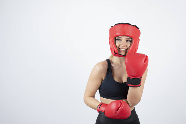 Kırmızı eldivenli ve kask dövüşü yapan genç bir bayan boksör. Yüksek kalite fotoğraf - Fotoğraf, Görsel