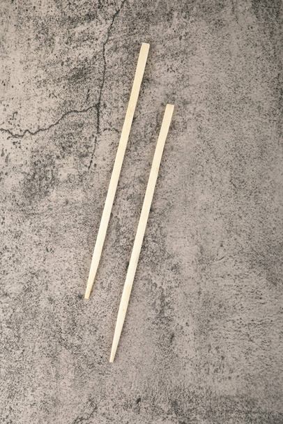 Two wooden chopsticks for eating sushi on stone background. High quality photo - Foto, Imagem