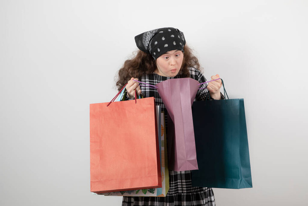 Ritratto di ragazza con sindrome di Down che guarda un mucchio di shopping bag. Foto di alta qualità - Foto, immagini