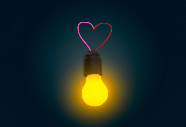 Glowing light bulb in lamp socket with electrical wires in the shape of a heart in the dark. - Valokuva, kuva