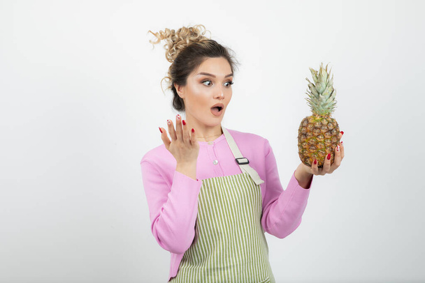 Image of beautiful young woman in apron holding ripe pineapple. High quality photo - Photo, image