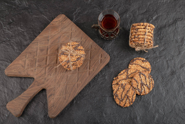 Top view of Pile of fresh cookies with tea on wooden cutting board. High quality photo - Photo, Image