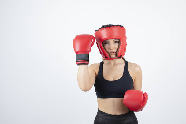 Kırmızı eldivenli ve kask eğitimli genç bayan boksör portresi. Yüksek kalite fotoğraf - Fotoğraf, Görsel