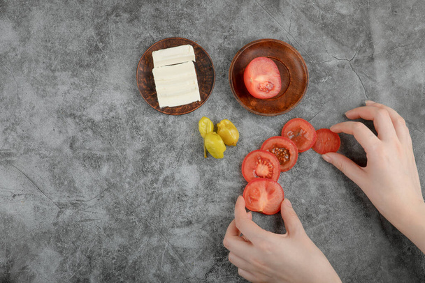 Γυναικεία χέρια που κρατούν φρέσκιες ντομάτες σε πέτρινο φόντο. Υψηλής ποιότητας φωτογραφία - Φωτογραφία, εικόνα