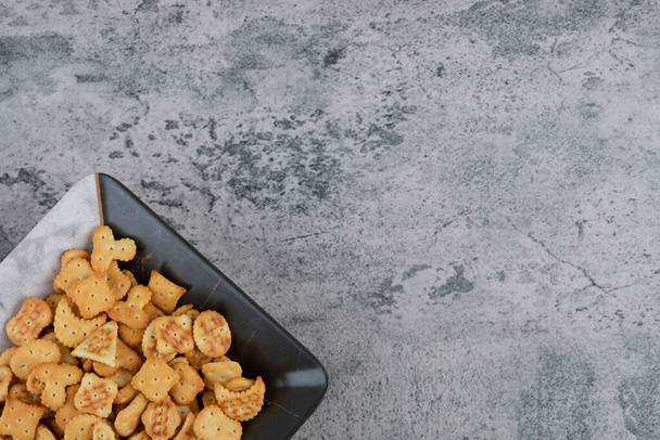 Plate full of dry salted crackers on marble background. High quality photo - Foto, Imagem
