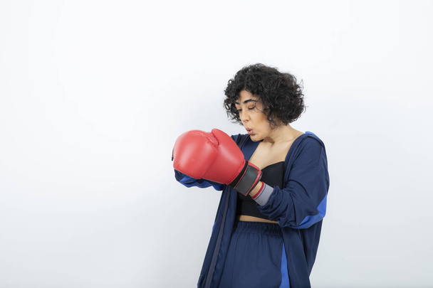 Photo of curly haired female athlete taking off red gloves. High quality photo - Foto, immagini