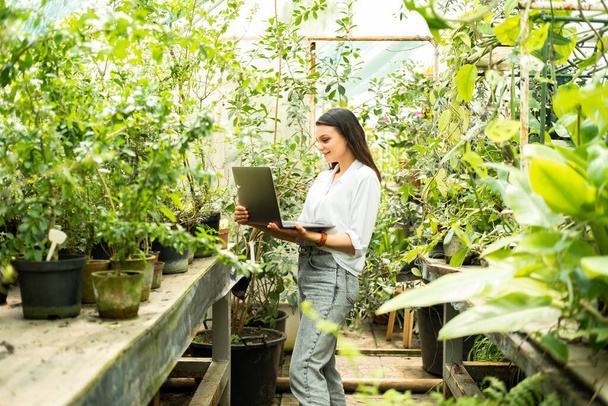 attractive business women gardener using laptop. Modern technology in gardening business - Photo, Image