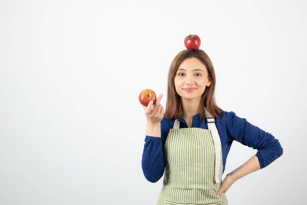 Bild einer jungen Frau mit roten Äpfeln, während sie auf weißem Hintergrund lächelt. Hochwertiges Foto - Foto, Bild