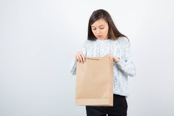 Photo of teen girl in sweater looking inside of craft bag. High quality photo - Fotoğraf, Görsel