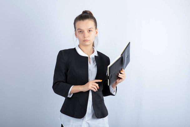 Portrait of young female teacher holding notebook on white background. High quality photo - Zdjęcie, obraz