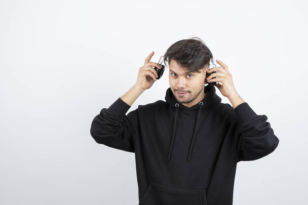 Handsome young man in black hoodie wearing big wireless music headphones . High quality photo - Foto, Imagem