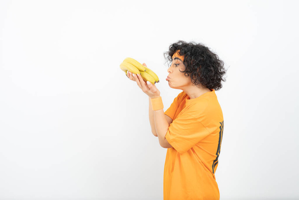Afrikanische Amerikanerin mit gelben Haaren und einer Banane auf weißem Hintergrund - Foto, Bild