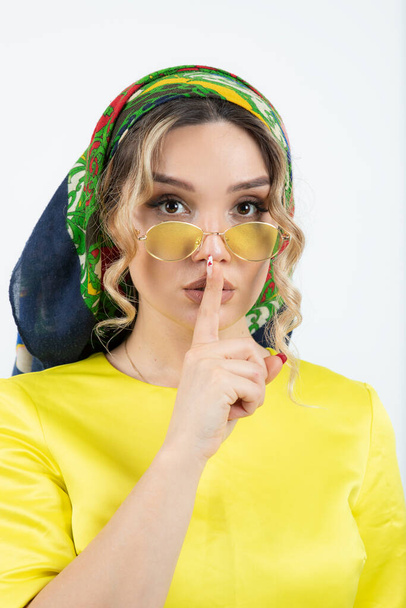 Photo of cute woman in headkerchief doing silent sign and posing in glasses . High quality photo - Fotó, kép