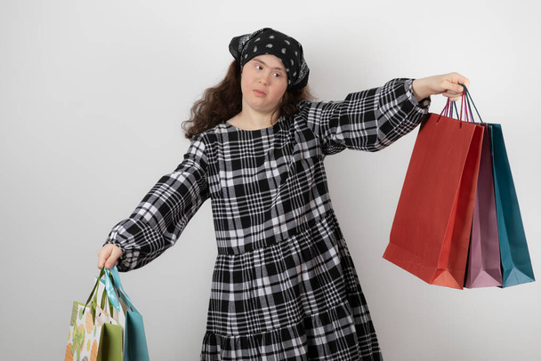 Retrato de una joven con síndrome de Down sosteniendo un montón de bolsa de la compra. Foto de alta calidad - Foto, Imagen