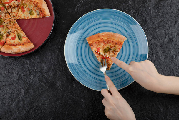 Ženské ruce berou plátek pizzy z talíře na černém pozadí. Kvalitní fotografie - Fotografie, Obrázek