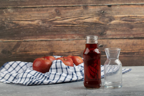 Friss érett vörös alma gyümölcslével egy üvegkancsóban, fából készült háttérrel. Kiváló minőségű fénykép - Fotó, kép