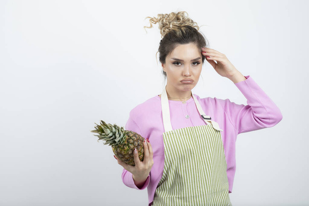 Image d'une belle jeune femme dans un tablier tenant de l'ananas mûr. Photo de haute qualité - Photo, image