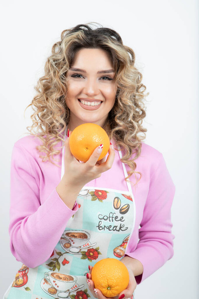 Photo of beautiful housewife with fresh oranges posing over white. High quality photo - Fotografie, Obrázek