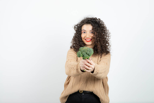 Bella donna in maglione lavorato a maglia con sani broccoli in piedi. Foto di alta qualità - Foto, immagini
