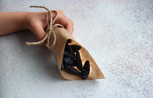 hands of a child with a paper bag with a honeysuckle berry - Foto, imagen