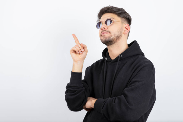 Photo of young handsome man in glasses standing and pointing. High quality photo - Foto, immagini