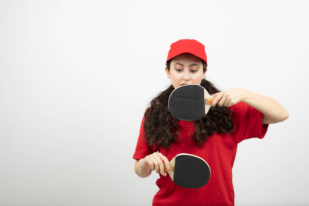 赤の制服を着たブルネットの女性が卓球ラケットを持っています。高品質の写真 - 写真・画像