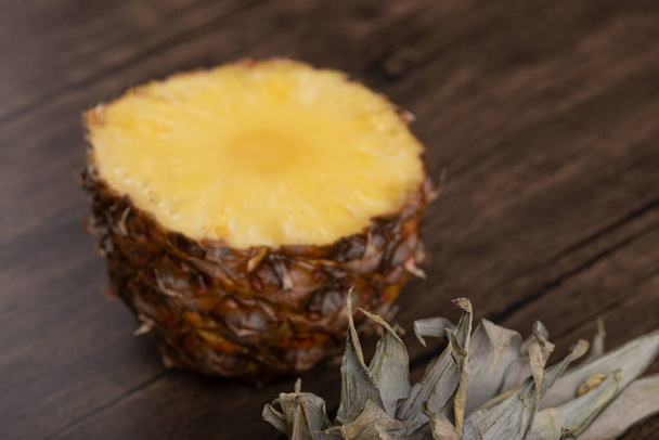 Herkullinen puoli viipaloitu kypsä ananas sijoitetaan puinen tausta. Laadukas kuva - Valokuva, kuva