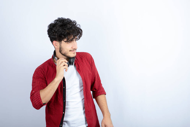 Imagen de un joven con auriculares mirando su costado sobre fondo blanco. Foto de alta calidad - Foto, Imagen