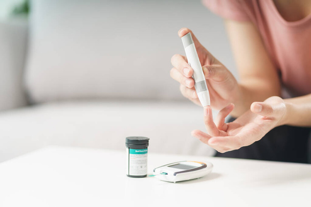 Kan şekeri seviyesini Glikoz ölçer, Sağlık ve Sağlık, Diyabet, glisemi konseptine göre ölçmek için parmak üzerine mızrak kullanan Asyalı kadın. - Fotoğraf, Görsel