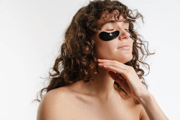 Half-naked european woman posing with eye patches isolated over white background - Фото, изображение