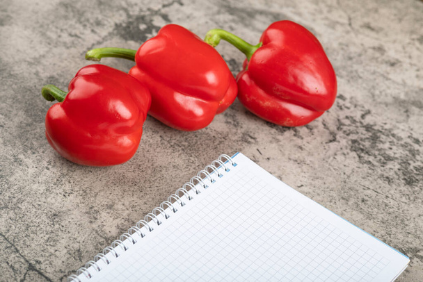 Süße rote Paprika und leeres Notizbuch auf Steinoberfläche. Hochwertiges Foto - Foto, Bild