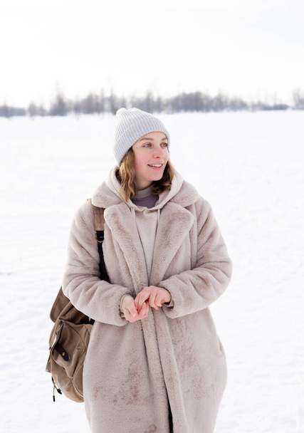 Νεαρό κορίτσι σε μπεζ ρούχα, γούνινο παλτό κατασκευασμένο από τεχνητή γούνα βόλτες το χειμώνα - Φωτογραφία, εικόνα