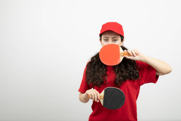 Bruneta v červené uniformě drží rakety na stolní tenis. Kvalitní fotografie - Fotografie, Obrázek